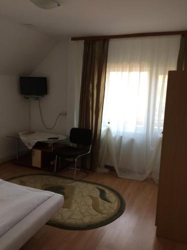 a bedroom with a bed and a chair and a window at Pensiunea Kristine Sibiu in Sibiu