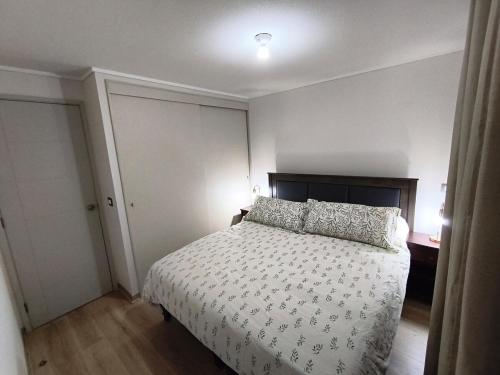 a bedroom with a bed with a white comforter at Nuevo departamento cercano a playa y comercio in Viña del Mar