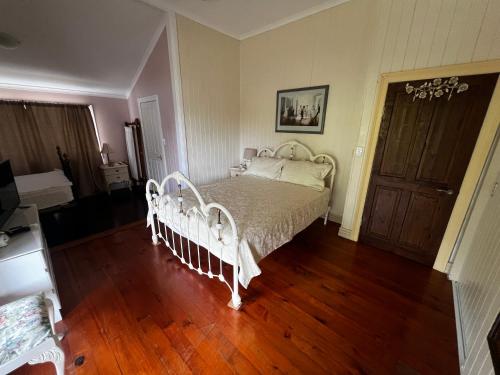 a bedroom with a white bed and a wooden floor at Homestead BnB in Maudsland