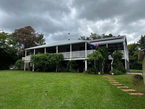 a large white house with a porch and a yard at Homestead BnB in Maudsland