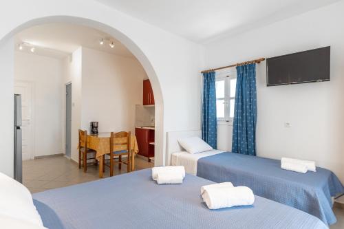a room with two beds and a kitchen with a table at Crystal Naxos 1 Studios at Mikri Vigla in Mikri Vigla