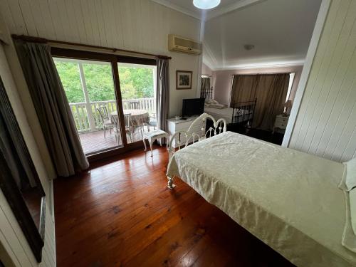 a bedroom with a bed and a living room with a balcony at Homestead BnB in Maudsland