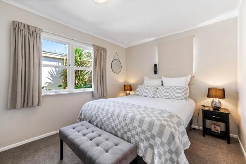 a bedroom with a large bed and a window at Silver Seas Retreat in Muriwai Beach