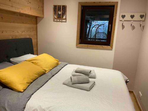 a bed with yellow and gray pillows on it at Superbe terrasse proximité centre in Morzine