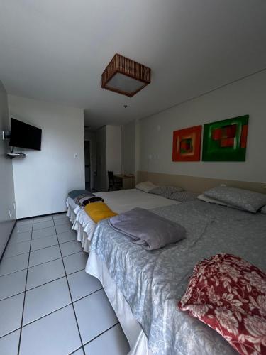 a bedroom with two beds and a tv on the wall at Condomínio Lençóis Flat Resdence in Barreirinhas