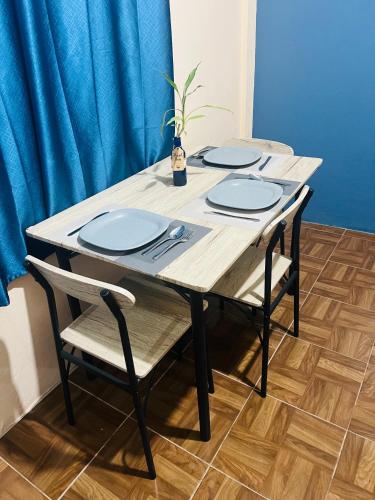 a wooden table with four chairs and blue plates at Departamento Flores in Catemaco