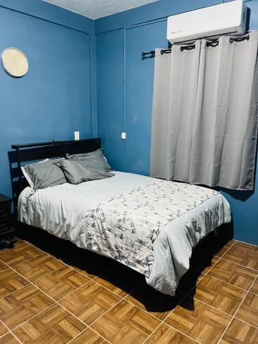 a bedroom with a bed with a blue wall at Departamento Flores in Catemaco