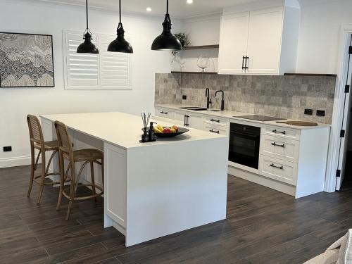 een keuken met witte kasten en een keukeneiland met stoelen bij Dawson's Retreat in Blewitts Springs