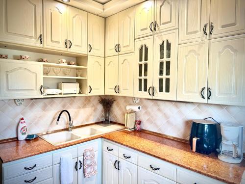 una cucina con mobili bianchi e un lavandino di Termál Apartman a Tiszaújváros