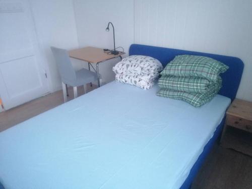 a blue bed with pillows and a table in a room at The top half of a house with sea view in Steinkjer