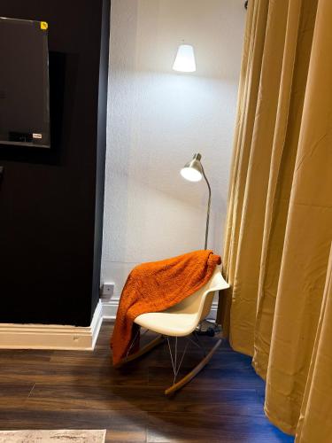 a chair with an orange blanket on it next to a lamp at Spacious 3 Bed , Free Parking , Fast WiFi , Long Stays in Kettering