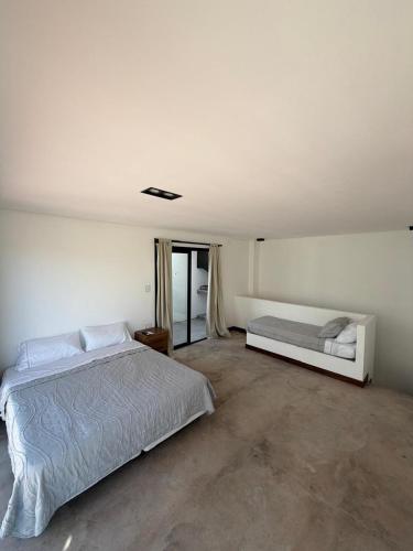 a white bedroom with a bed and a window at Vilaggio Magnolia in Cafayate