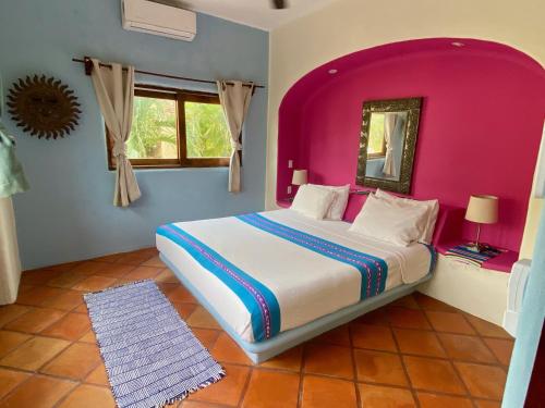 a bedroom with a large bed with a pink wall at Casa MoJo - Whole house 7BR, heated pool, WiFi in Sayulita