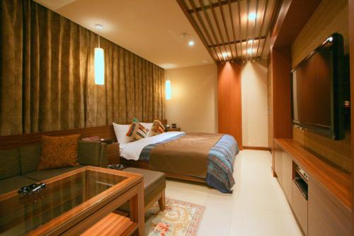 a hotel room with a bed and a tv at Hotel Aura Daito (Adult Only) in Daitō