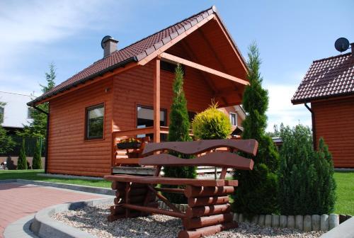a log cabin with a bench in front of it at Domki Wczasowe Papaya in Kołobrzeg