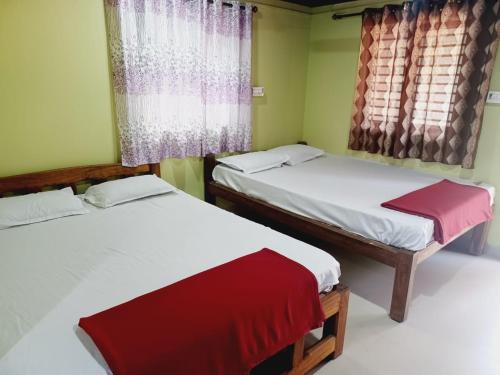 two twin beds in a room with two windows at Gokarna Royal Cottage in Gokarna
