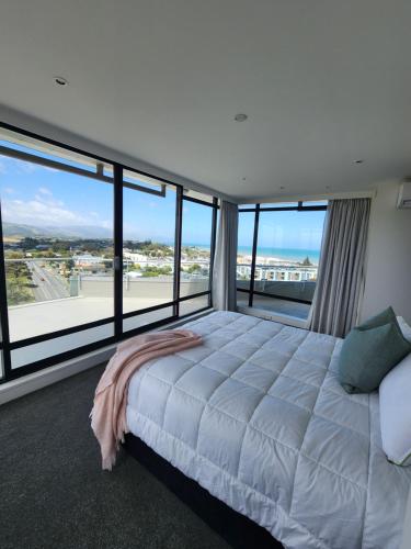 a bedroom with a large bed and large windows at U Suites at The Links in Paraparaumu