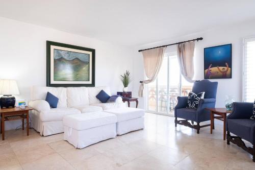 a living room with a white couch and blue chairs at Playa Blanca Condo in Tijuana