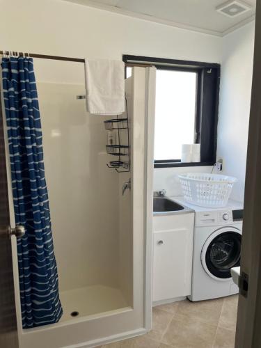 a bathroom with a sink and a washing machine at Stanmore Bay Log Cabin - short walk to beach in Stanmore Bay