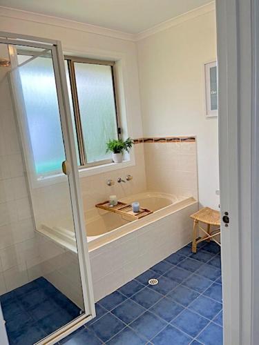 a bathroom with a bath tub and a window at Coastal Calm in Normanville