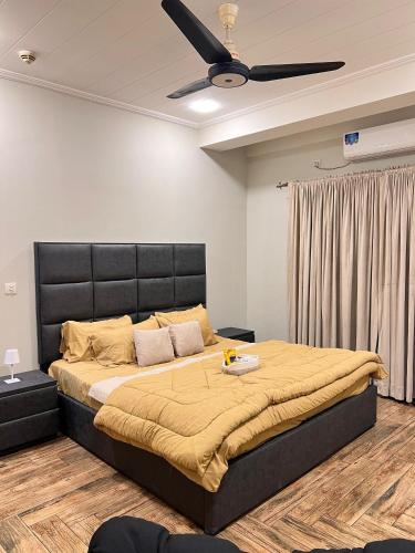 a bedroom with a large bed with a ceiling fan at Designer 1 bedroom , self check-in , pool & sauna in Rawalpindi