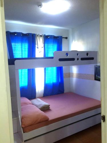 a bedroom with a bunk bed with blue curtains at Janna's Condo Hotel in Cebu City
