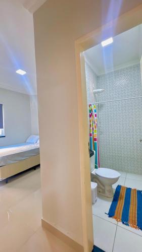 a bathroom with a shower and a toilet and a bed at CASA MARIANNA em Paracuru - Piscina, 3 quartos, ar condicionado e perto de tudo! in Paracuru