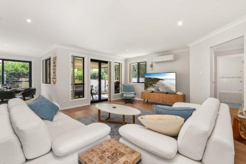 a living room with a white couch and a table at White Sands Villa by Experience Jervis Bay in Huskisson