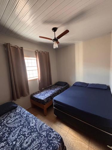 a bedroom with two beds and a ceiling fan at Recanto Lemes in Olímpia