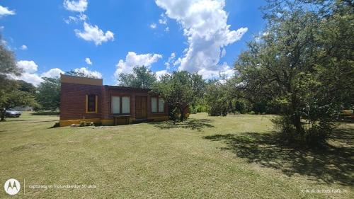a small house on a grassy yard with trees at El Espinillo, Casa de Campo in Santa Rosa de Calamuchita
