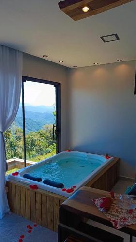 a large hot tub in a room with a large window at Chalé Refugio nas montanhas in Guaratuba