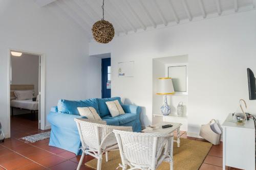 a living room with a blue couch and chairs at Quo Mosteiros Sunset House in Mosteiros