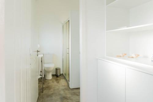a white bathroom with a toilet and a sink at Quo Mosteiros Sunset House in Mosteiros