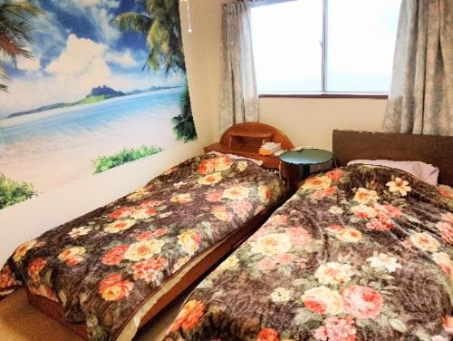 two beds in a room with a painting of a beach at Futami Terrace C in Ise