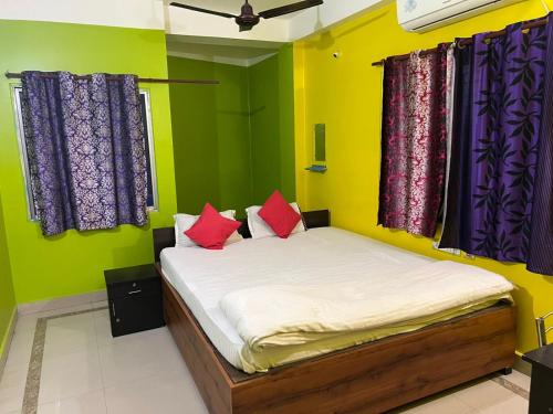 a bedroom with a bed with colorful walls and windows at Radha Rani lodge in Siliguri