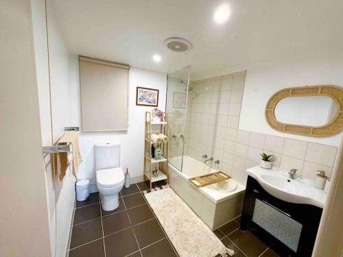a bathroom with a toilet and a tub and a sink at Mountain View Spa Cottage in The Basin