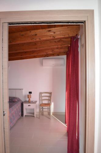 a bedroom with a bed and a red curtain at Terrazza sul golfo degli angeli in Capitana
