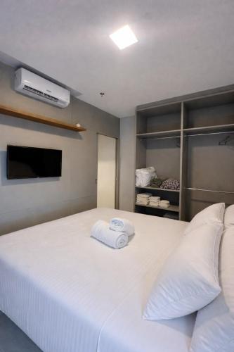 a bedroom with a large white bed with a flat screen tv at Flat novo próximo ao Hard Rock in Itapema