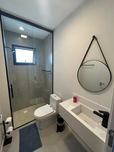 a bathroom with a toilet and a sink and a mirror at Flat novo próximo ao Hard Rock in Itapema