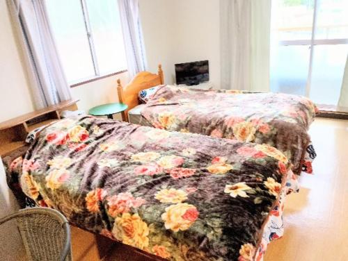 a bedroom with two beds with a flowered blanket at Futami Terrace B in Ise