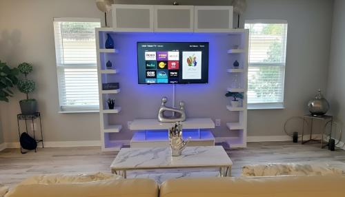 a living room with a couch and a tv on the wall at Welcome to Tranquility House in Tampa