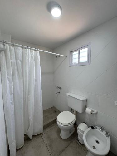 a white bathroom with a toilet and a window at Merlinda in Merlo