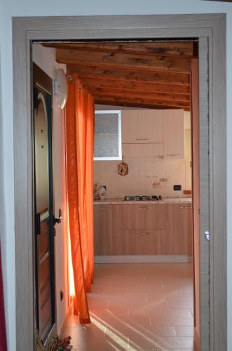 an open door into a kitchen with an orange curtain at Terrazza sul golfo degli angeli in Capitana