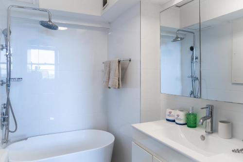 a white bathroom with a tub and a sink at Central CBD High-Level Apartment with Views in Sydney