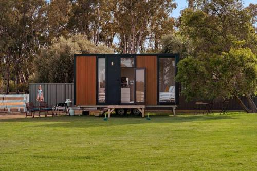 a tiny house sitting on a grass field at Murray Haven Farm Stay by Tiny Away in Koonoomoo