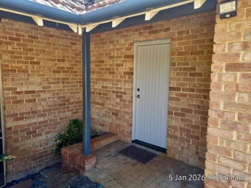 a brick house with a white door and a brick wall at Angel Apartment in Perth