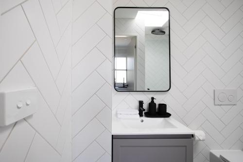 a white bathroom with a sink and a mirror at Central 3BR Glebe with Free Street Parking & Pet Friendly - Walk to Markets & Cafes in Sydney