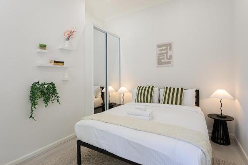 a white bedroom with a bed and a mirror at Central 3BR Glebe with Free Street Parking & Pet Friendly - Walk to Markets & Cafes in Sydney