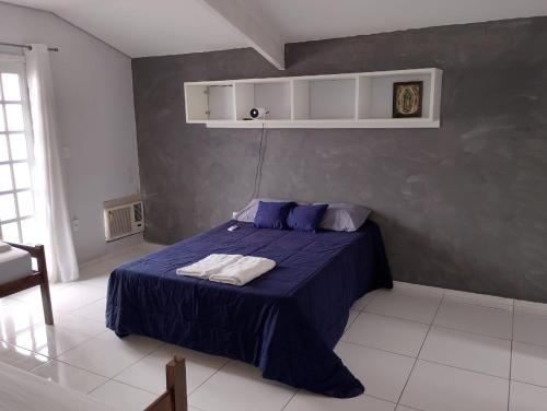 een slaapkamer met een bed met blauwe lakens en blauwe kussens bij Pousada Utopia in Aparecida