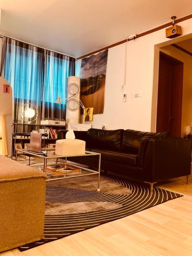 a living room with a black leather couch and a rug at Stay Banwoldang in Daegu